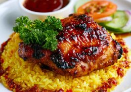 Honey BBQ chicken served over fluffy rice, glazed with a sweet and smoky sauce and garnished with green onions and sesame seeds.
