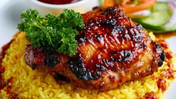 Honey BBQ chicken served over fluffy rice, glazed with a sweet and smoky sauce and garnished with green onions and sesame seeds.