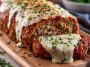 Garlic Parmesan meatloaf sliced on a plate with herbs and sauce