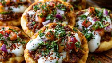 Mini lahmacun bites topped with spiced meat and yogurt drizzle.