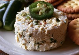 Roasted jalapeño cowboy cream cheese dip topped with crispy bacon, green onions, and melted cheese served warm with crackers.