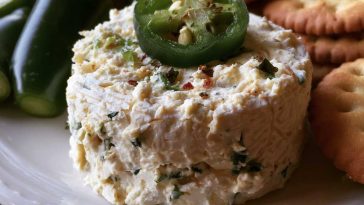 Roasted jalapeño cowboy cream cheese dip topped with crispy bacon, green onions, and melted cheese served warm with crackers.