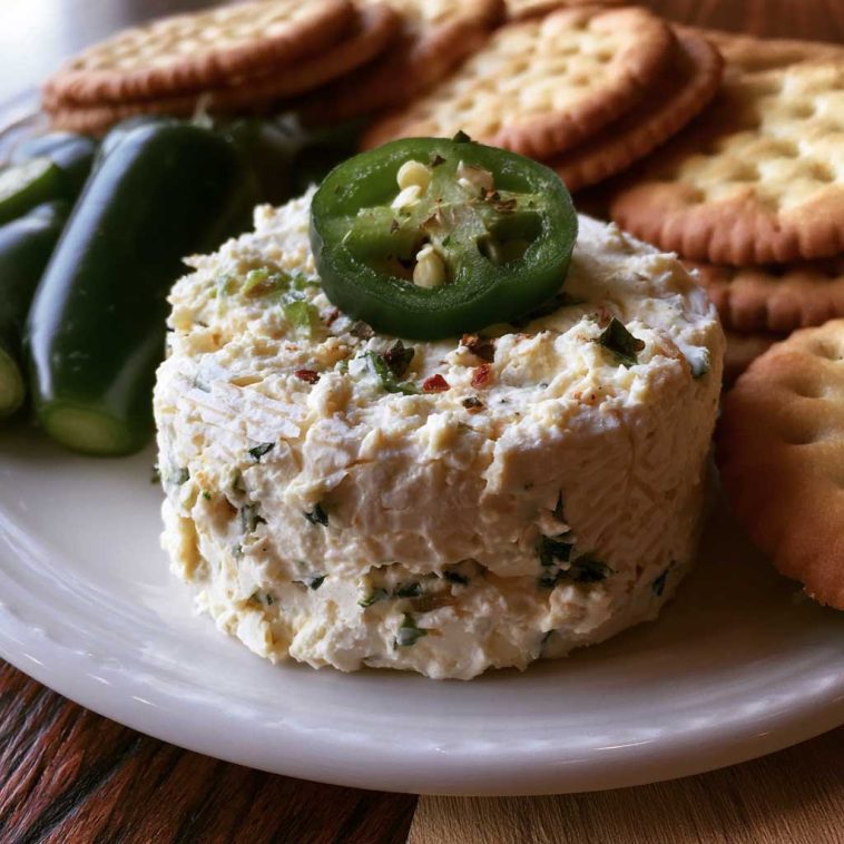 Roasted jalapeño cowboy cream cheese dip topped with crispy bacon, green onions, and melted cheese served warm with crackers.