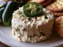 Roasted jalapeño cowboy cream cheese dip topped with crispy bacon, green onions, and melted cheese served warm with crackers.