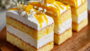 Moist mango milk cake topped with fresh mango pieces and creamy layers.