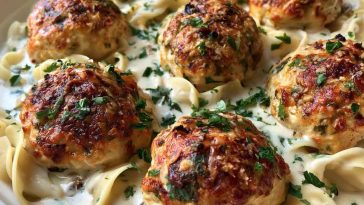 Chicken ricotta meatballs simmered in creamy Alfredo sauce served in a skillet