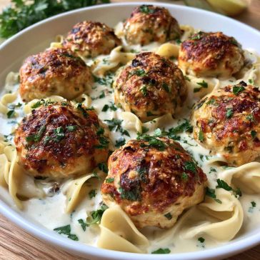 Chicken ricotta meatballs simmered in creamy Alfredo sauce served in a skillet