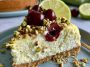 Refreshing cheesecake with layers of lemon lime filling, cherry topping, and a pistachio crust, garnished with whipped cream and chopped nuts.