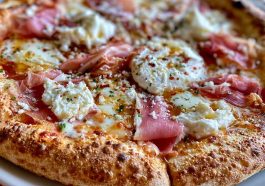 Gourmet prosciutto honey burrata pizza topped with creamy burrata cheese, thin prosciutto slices, fresh herbs, and a drizzle of honey.