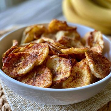Crispy air fryer banana chips coated in cinnamon sugar, arranged in a bowl for a healthy homemade snack.