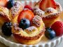 Mini German pancakes puffed and golden, topped with powdered sugar and berries.