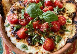 Warm caprese dip with melted mozzarella, cherry tomatoes, and fresh basil, drizzled with balsamic glaze and served with toasted bread.