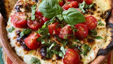 Warm caprese dip with melted mozzarella, cherry tomatoes, and fresh basil, drizzled with balsamic glaze and served with toasted bread.
