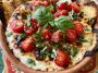 Warm caprese dip with melted mozzarella, cherry tomatoes, and fresh basil, drizzled with balsamic glaze and served with toasted bread.
