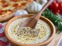 Creamy garlic sauce served in a bowl alongside pizza slices.