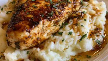 Juicy glazed garlic herb chicken breast served over creamy mashed potatoes with rich pan sauce drizzled on top.