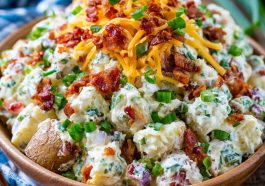 Creamy loaded potato salad with tender potatoes, crispy bacon, shredded cheese, green onions, and a rich dressing.