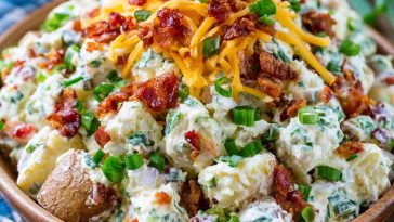 Creamy loaded potato salad with tender potatoes, crispy bacon, shredded cheese, green onions, and a rich dressing.