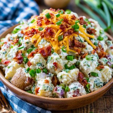 Creamy loaded potato salad with tender potatoes, crispy bacon, shredded cheese, green onions, and a rich dressing.