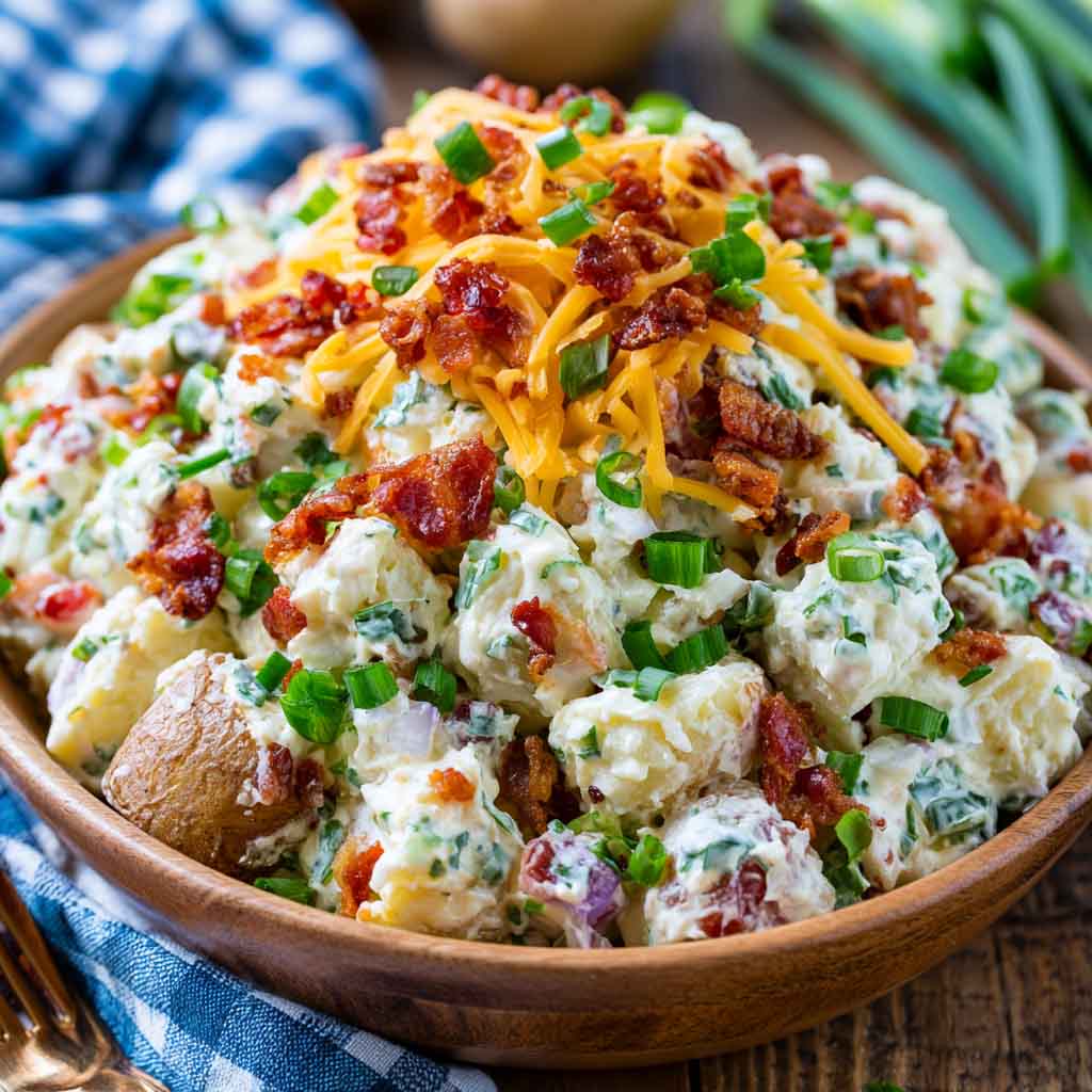 Creamy loaded potato salad with tender potatoes, crispy bacon, shredded cheese, green onions, and a rich dressing.