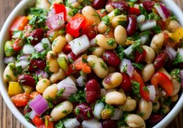 Colorful bean salad with mixed beans, fresh vegetables, herbs, and a tangy vinaigrette in a serving bowl.
