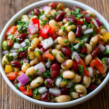 Colorful bean salad with mixed beans, fresh vegetables, herbs, and a tangy vinaigrette in a serving bowl.
