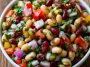 Colorful bean salad with mixed beans, fresh vegetables, herbs, and a tangy vinaigrette in a serving bowl.