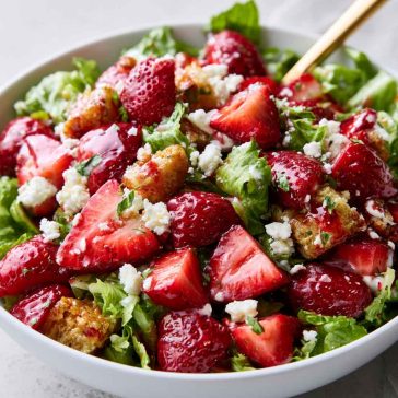 Fresh strawberry crackle salad with juicy strawberries, crunchy toppings, creamy dressing, and greens in a bowl.