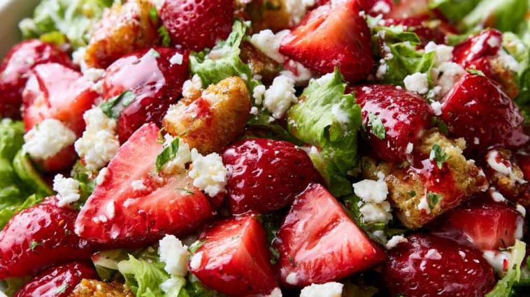 Fresh strawberry crackle salad with juicy strawberries, crunchy toppings, creamy dressing, and greens in a bowl.