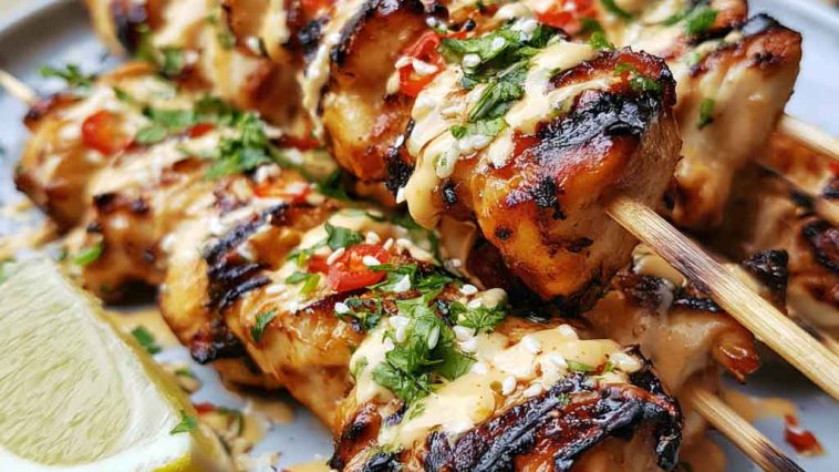 Bang bang chicken skewers glazed with creamy spicy sauce and grilled.