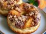 Peach cobbler cheesecake donuts topped with glazed peaches, creamy cheesecake filling, and crumb topping.