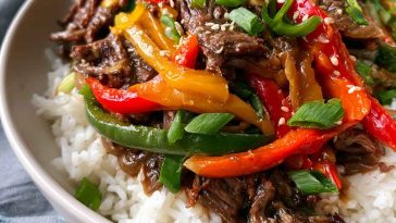 Healthy beef and pepper rice bowl with tender beef strips, colorful bell peppers, and fluffy rice, topped with fresh herbs.