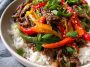 Healthy beef and pepper rice bowl with tender beef strips, colorful bell peppers, and fluffy rice, topped with fresh herbs.