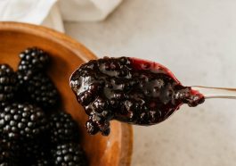 Homemade blackberry jam in a jar with fresh blackberries