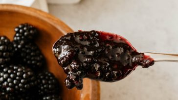 Homemade blackberry jam in a jar with fresh blackberries