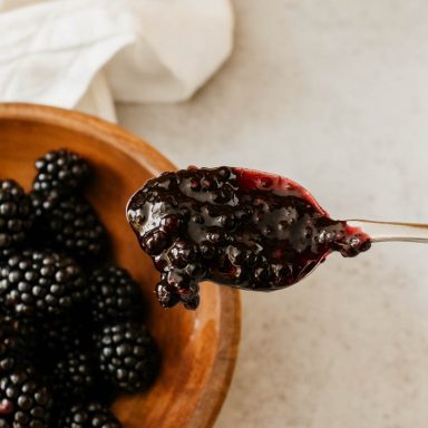 Homemade blackberry jam in a jar with fresh blackberries
