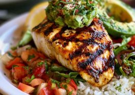 Grilled chicken breasts topped with fresh avocado slices, melted cheese, tomatoes, and herbs on a serving platter.
