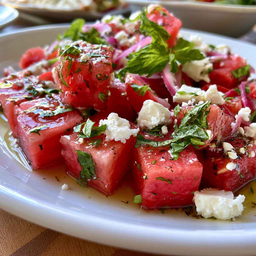 “Bowl of watermelon feta salad with fresh mint and lime dressing, served as a colorful summer side dish.”