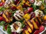 Peach burrata summer salad – Fresh peach slices with creamy burrata, basil, and arugula on a platter.