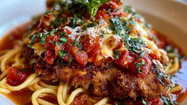Crispy Chicken Romano topped with Romano cheese crust, served with a creamy pasta side and garnished with fresh parsley.