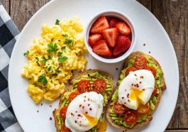 Healthy scrambled eggs with strawberries and avocado toast on a plate.Healthy Breakfast