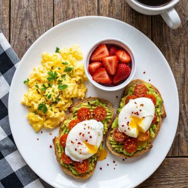 Healthy scrambled eggs with strawberries and avocado toast on a plate.Healthy Breakfast
