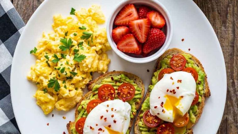 Healthy scrambled eggs with strawberries and avocado toast on a plate.Healthy Breakfast