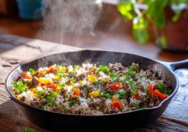 Ground Beef and Rice Skillet in a cast iron skillet with seasoned ground beef, fluffy white rice, diced bell peppers, onions, and melted cheddar cheese, topped with fresh parsley.