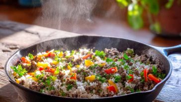 Ground Beef and Rice Skillet in a cast iron skillet with seasoned ground beef, fluffy white rice, diced bell peppers, onions, and melted cheddar cheese, topped with fresh parsley.