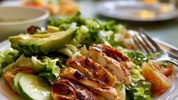 Fresh Chicken Avocado Salad with grilled chicken, sliced avocado, cherry tomatoes, cucumber, and mixed greens in a bowl.