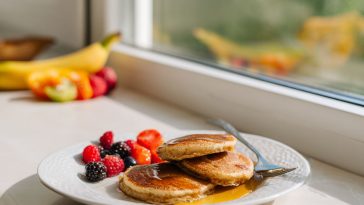 A stack of golden brown fluffy cottage cheese pancakes topped with fresh berries and a drizzle of maple syrup.